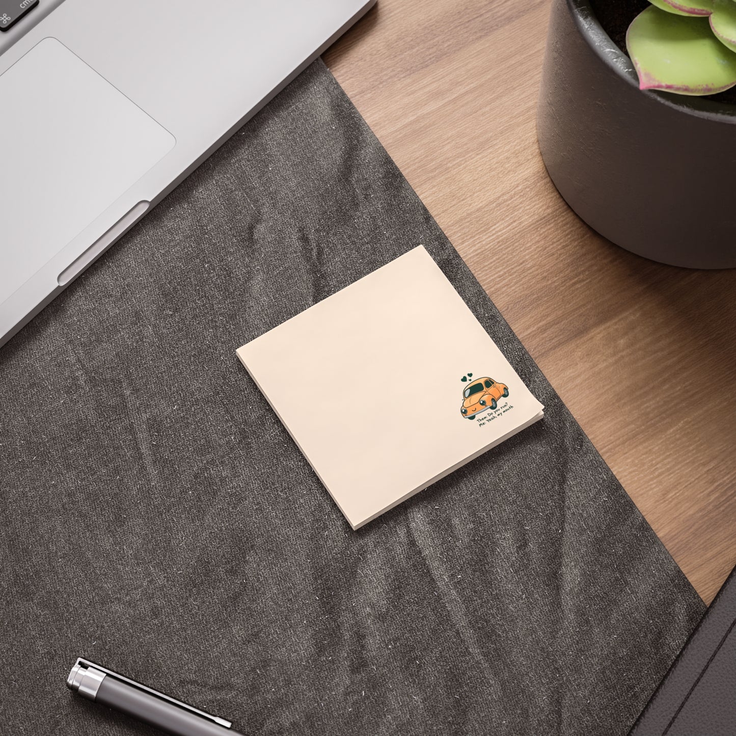 Notebook with a cartoon character on a desk next to a laptop and plant