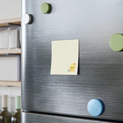 Square cream sticky note pad styled upright on a desk shelf with a small smiling star design in the lower corner.