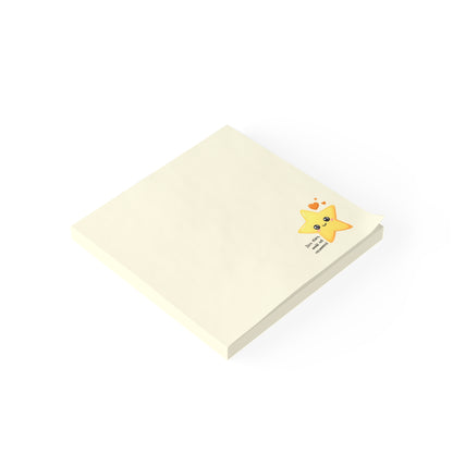 Angled product view of a square cream sticky note pad with a small smiling star design near the corner.