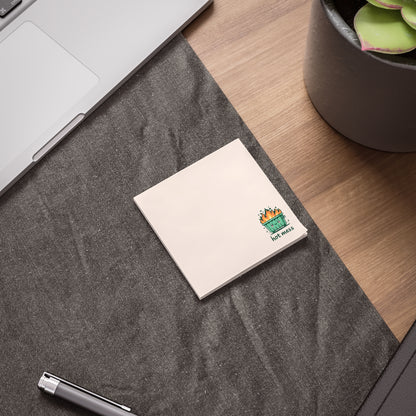 Notebook with a colorful design on a gray surface next to a laptop and plant