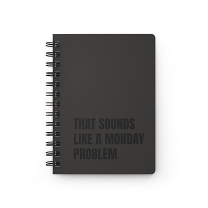 Black notebook with text 'That Sounds Like a Monday Problem' on a white background