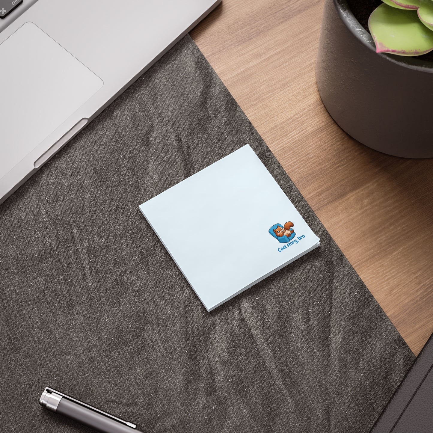 Light blue sticky note pad on a desk with a laptop, pen, and plant, featuring a small squirrel illustration in the corner.