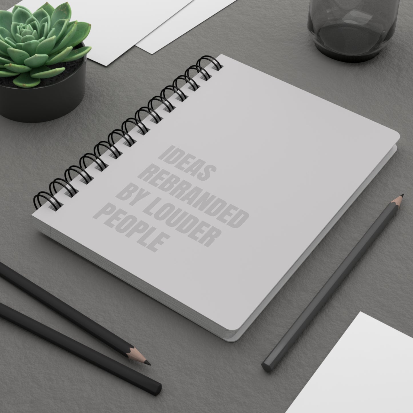 Notebook with text on a desk with pencils and a plant