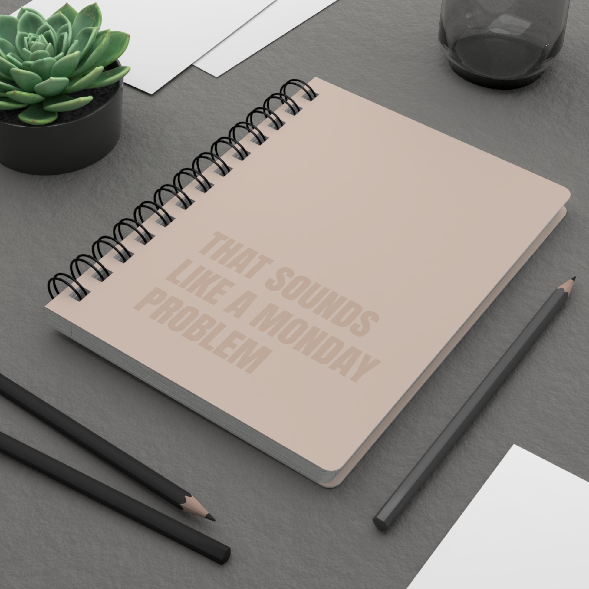 Notebook with text on a desk with pencils and a plant