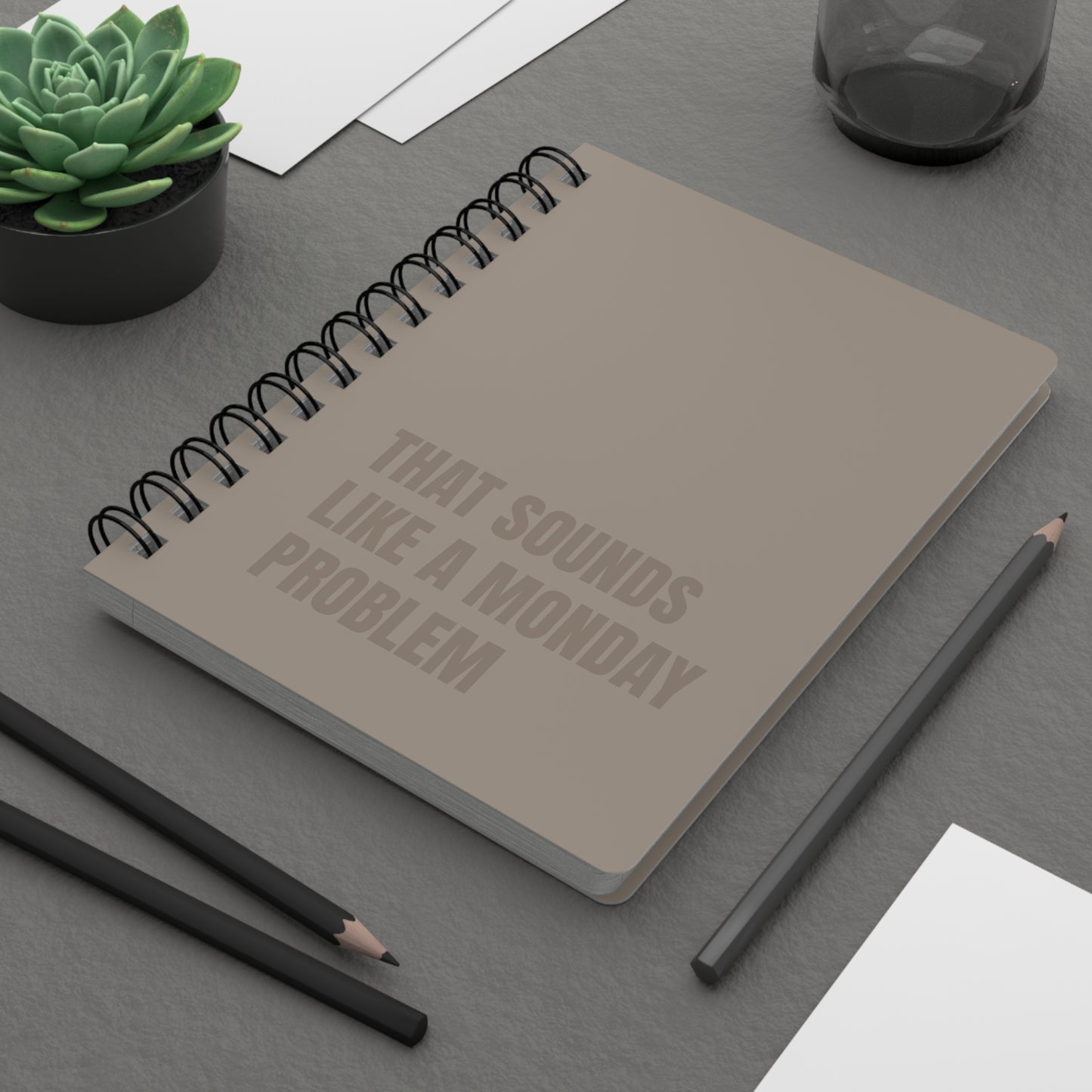 Notebook with text on a desk with pencils and a plant